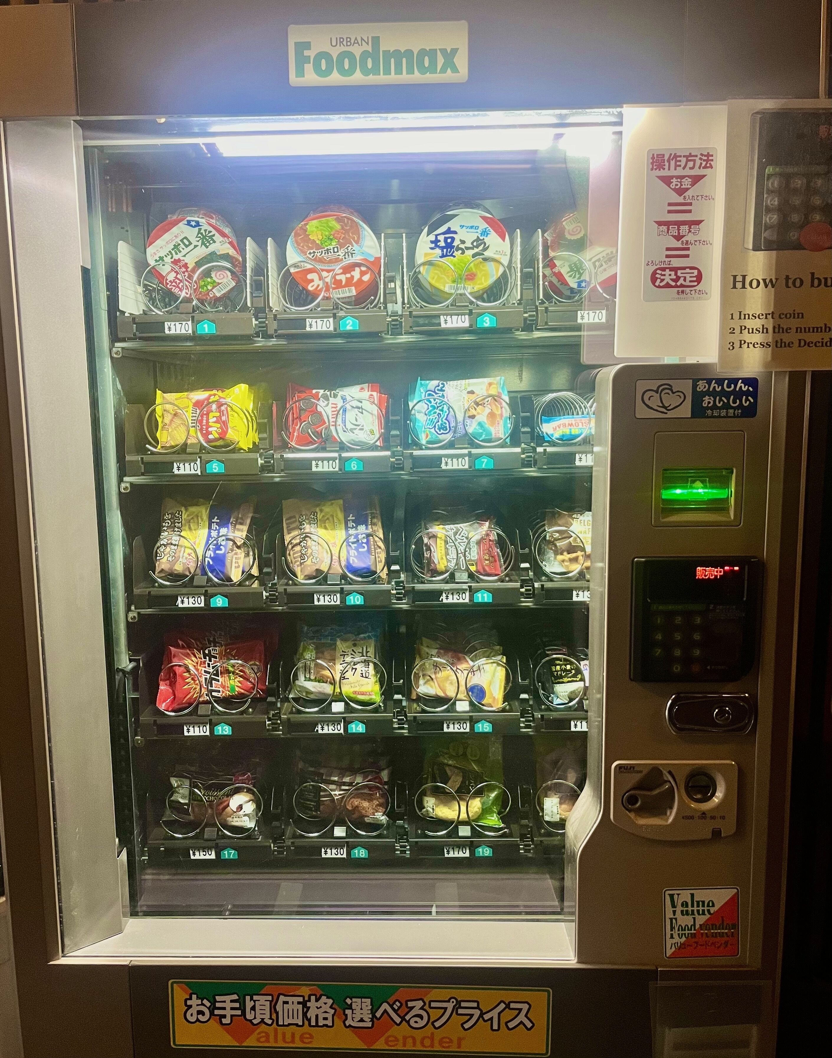 A vending machine with various snacks and drinks priced at ¥110, ¥130, and ¥170.
