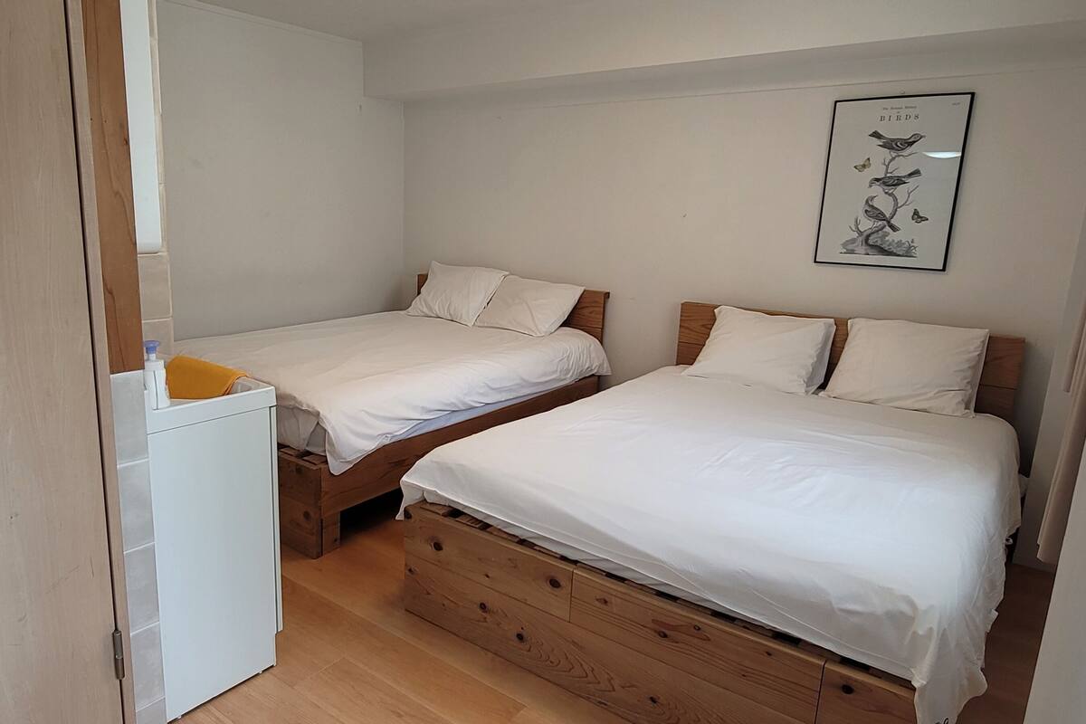 Un dormitorio con dos camas, un archivador blanco pequeño y un cuadro en la pared.