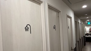 Un couloir d’hôtel avec des portes indiquant l’emplacement des équipements tels qu’une douche, des toilettes et un lit.