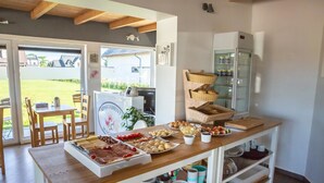 A buffet setup with various food items, a refrigerator, and a dining area with chairs and a table. - Apartamenty Magnolia (Wicko)