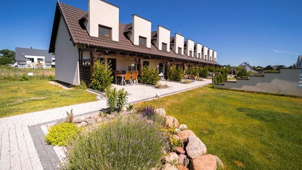 A row of modern, single-story buildings with a flat roof and a central courtyard. - Apartamenty Magnolia (Wicko)
