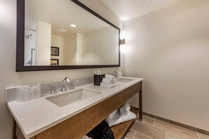 A bathroom with two sinks, a large mirror, and a wooden vanity.