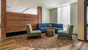 A modern hotel lobby with a blue sofa, two armchairs, a patterned rug, and wooden paneling. - Comfort Inn & Suites Pittsburgh-Northshore (Pittsburgh)
