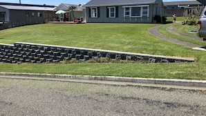 Un quartier résidentiel doté d’une pelouse bien entretenue, d’un mur de soutènement en pierre et de maisons à l’architecture similaire.