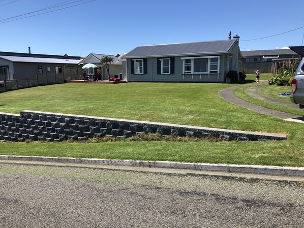 A residential area with a well-maintained lawn, a stone retaining wall, and houses with similar architecture.
