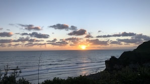 Un coucher de soleil sur la côte, avec un ciel dégagé et une mer calme.