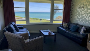 Un salon avec vue sur la mer, comprenant deux canapés, une table basse et des fauteuils en osier.