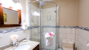 A bathroom with a glass-enclosed shower, a sink, a toilet, and a mirror. - The Great Escape in Belize's Best Tourist Destinations!! (Placencia)