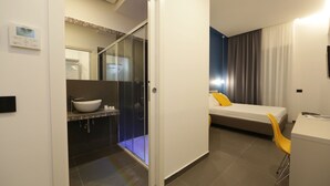A modern hotel room with a bathroom, a bed, and a desk. - Cellamare Suite & Spa (Naples)