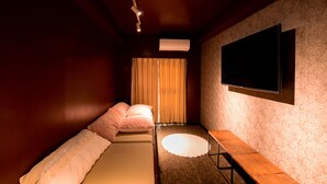 A room with a bed, a bench, a flat-screen TV mounted on the wall, and a patterned wall. - bnb+ Ueno Okachimachi - Hostel (Tokyo)