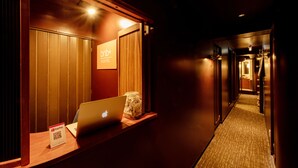 A hotel reception area with a laptop, a PayPal QR code sign, and a wooden counter. - bnb+ Ueno Okachimachi - Hostel (Tokyo)