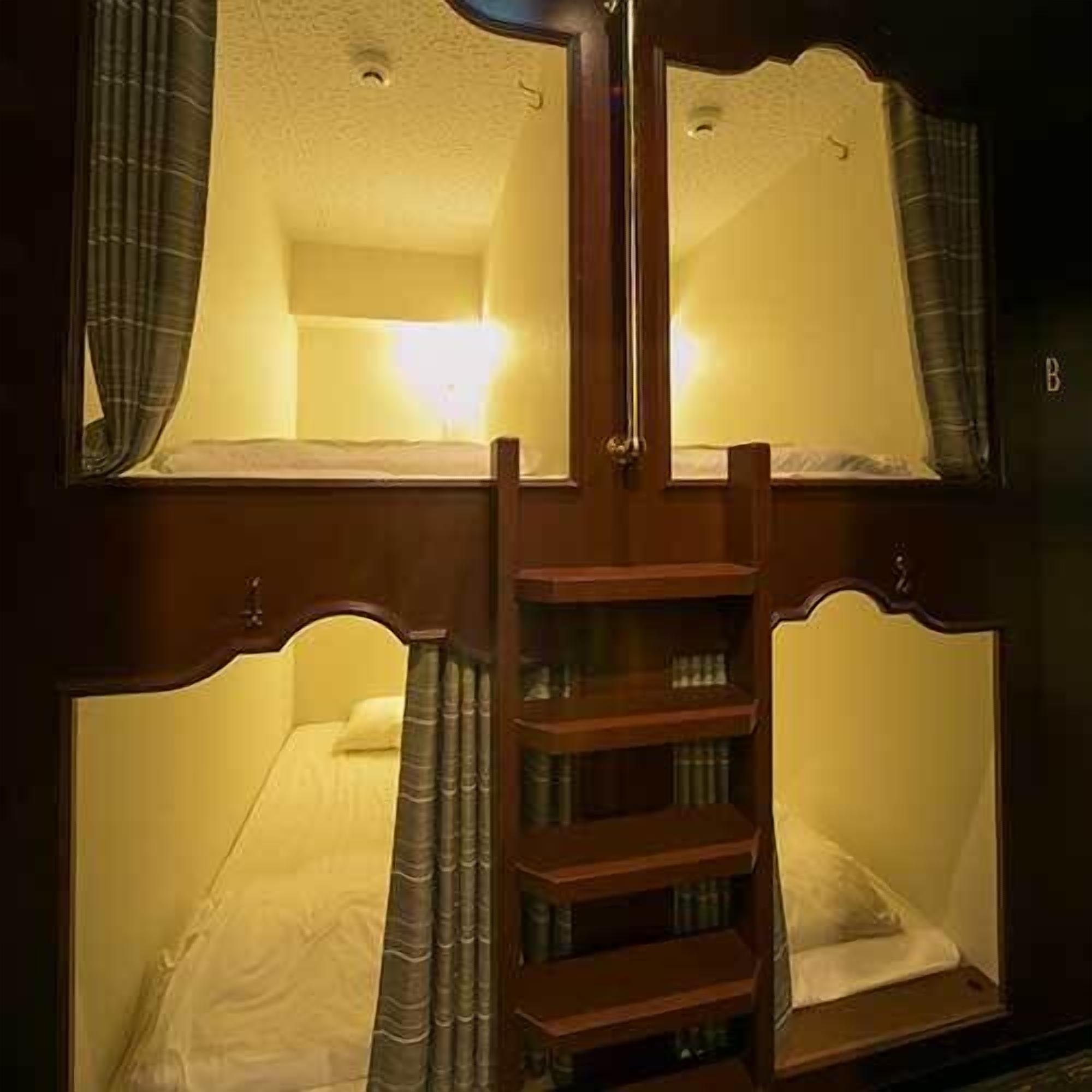A bunk bed with a wooden ladder, a bedside table, and a mirror.