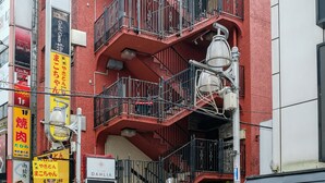 A multi-story building with balconies, a staircase, and various signs indicating businesses. - bnb+ Ueno Okachimachi - Hostel (Tokyo)
