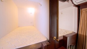 A small, compact bedroom with a single bed, a mirror, and a radiator. - bnb+ Ueno Okachimachi - Hostel (Tokyo)