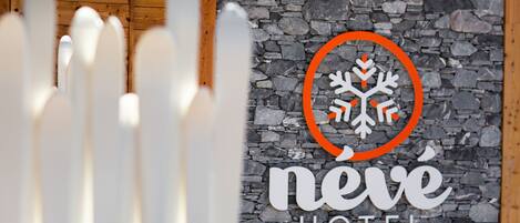 Hotellin kyltti, jossa on logo ja nimi ”neve HOTEL”, on kiinnitetty kiviseinään.