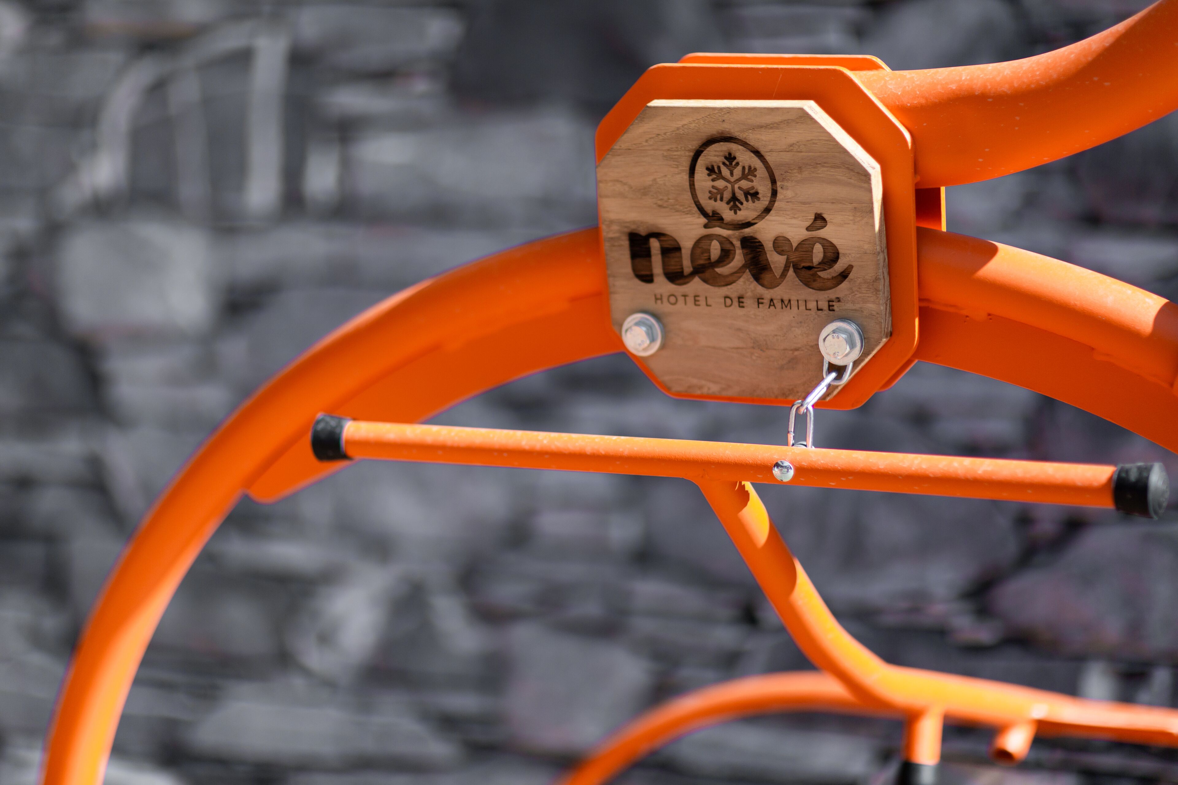 A wooden sign with the text "nave HOTEL DE FAMILLE" attached to an orange metal structure.