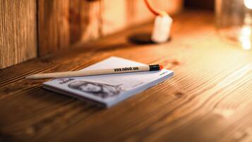 A wooden table with a pencil, a piece of paper, and a small white object.