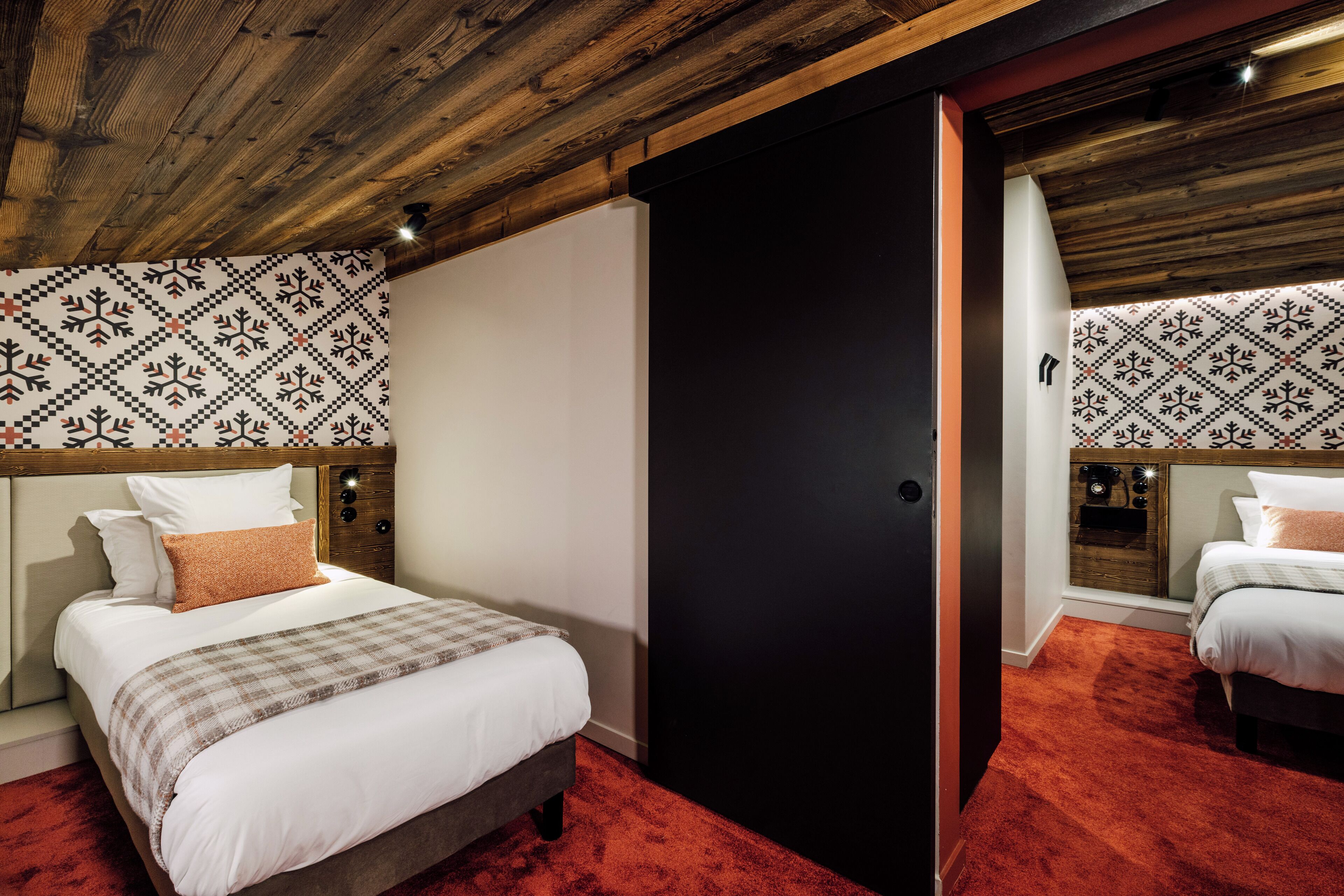 A hotel room with a large bed, a black door, and patterned wallpaper.