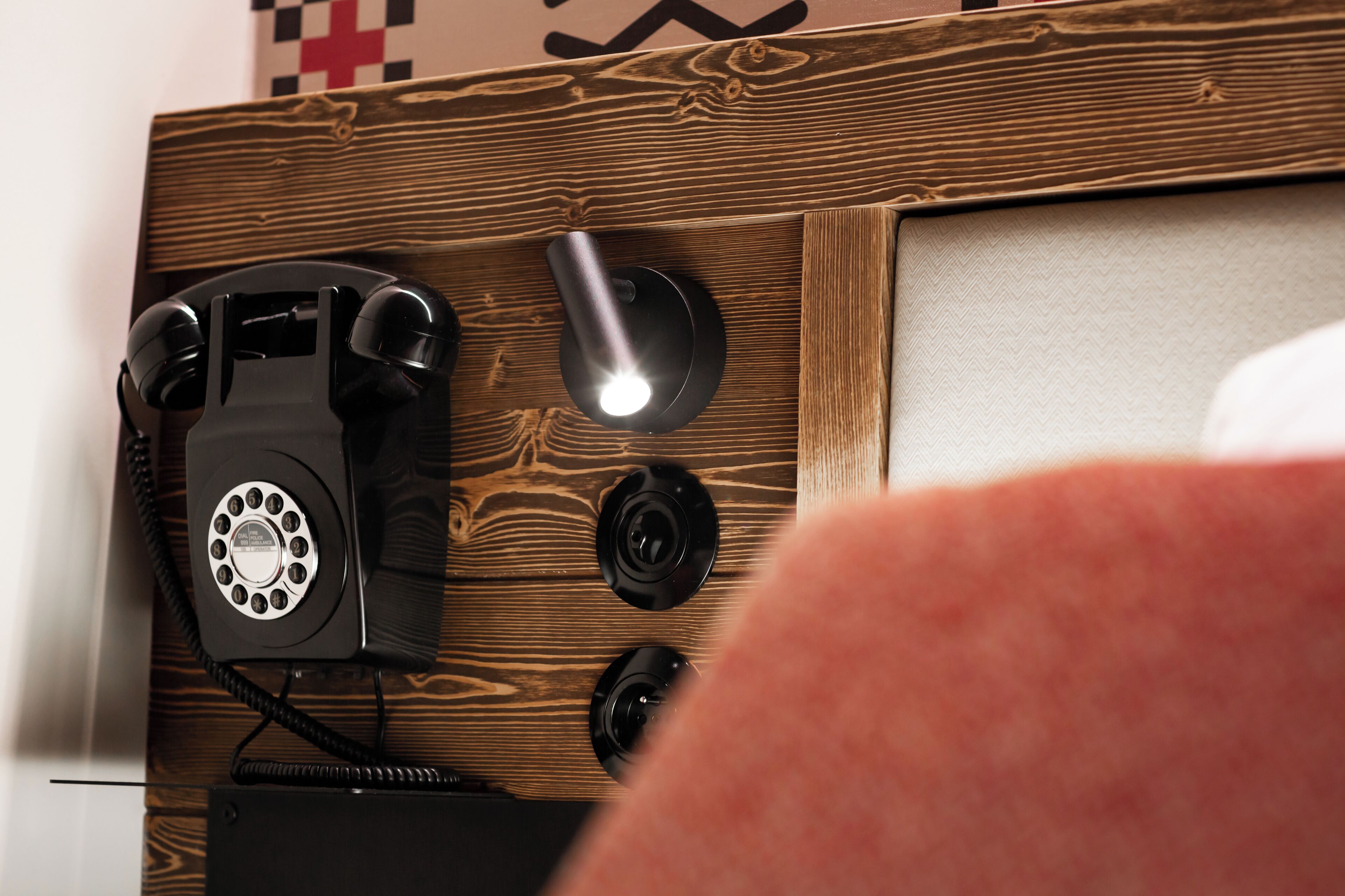 Un pannello di legno con un telefono a disco, un mouse e un piccolo oggetto nero, probabilmente un telecomando.