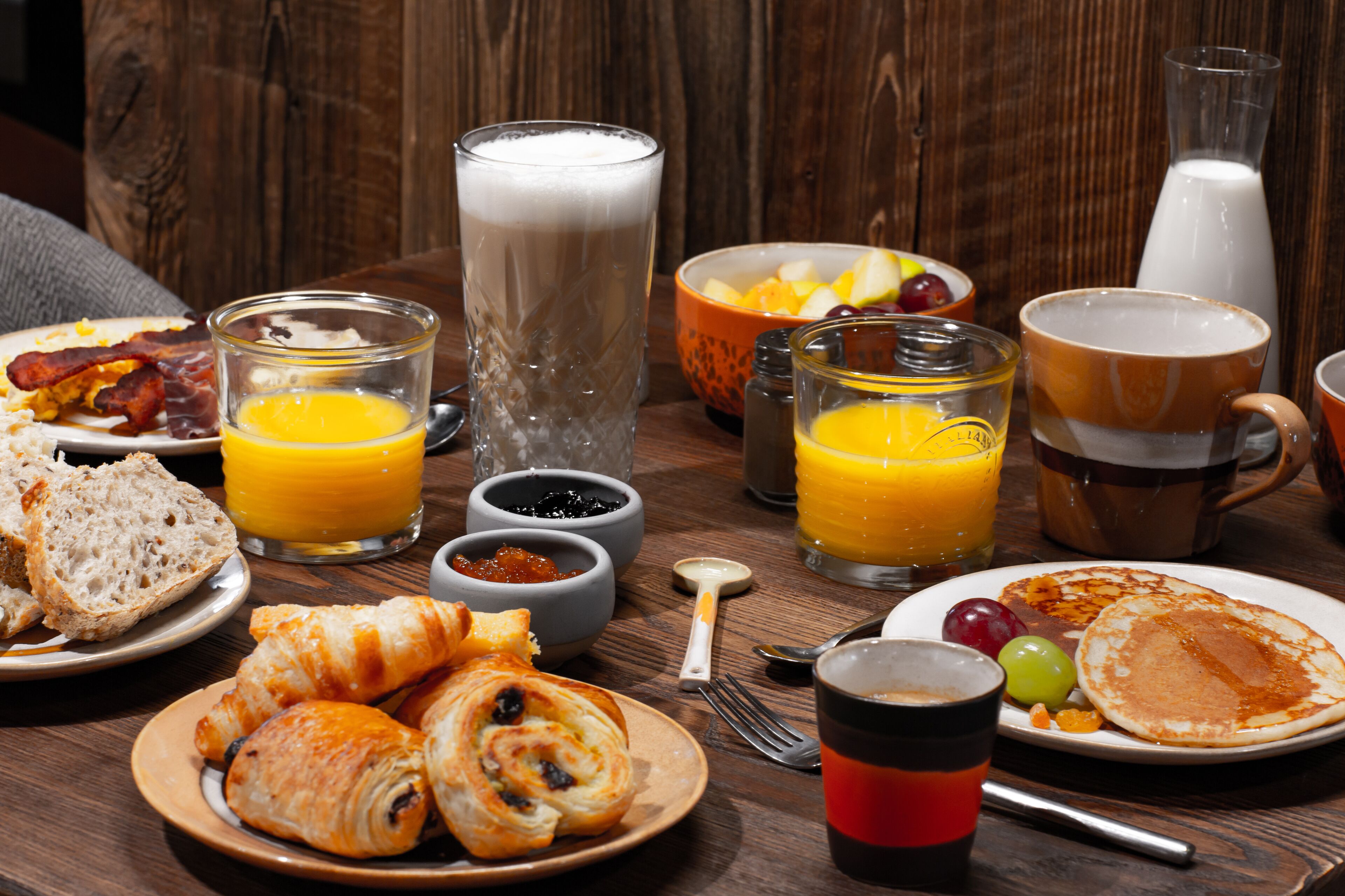 Une table de petit-déjeuner avec divers aliments, boissons et condiments.