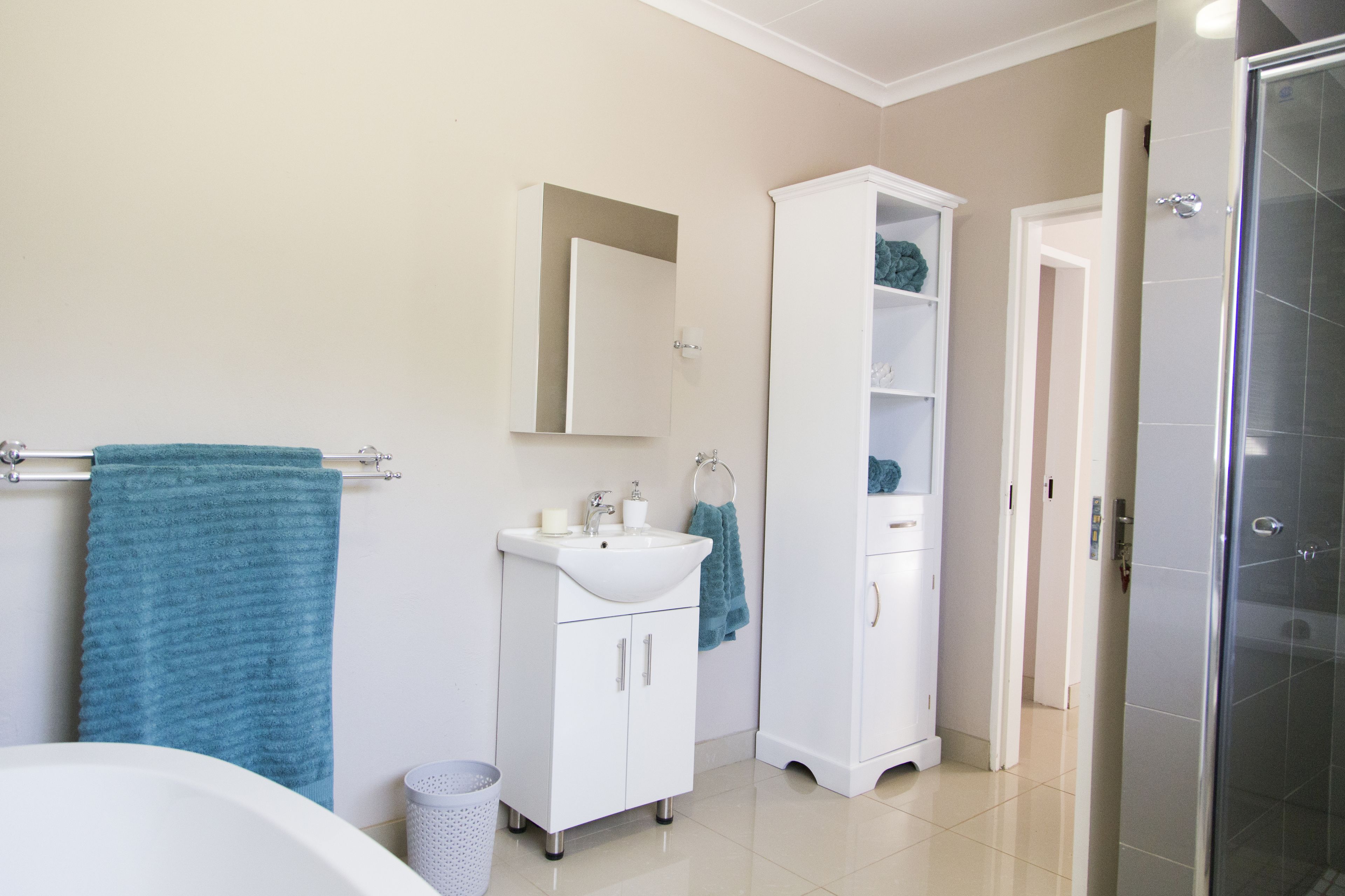 Un baño con bañera, lavamanos, espejo, armario y zona de ducha.
