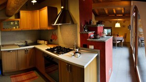 Een keuken met houten kastjes, een gasfornuis en een rode accentmuur.
