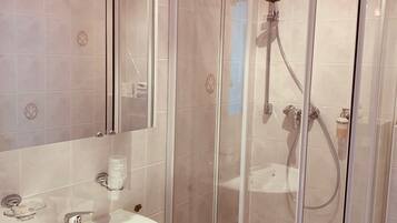 Une salle de bain avec une douche à parois de verre, un lavabo blanc et un miroir.