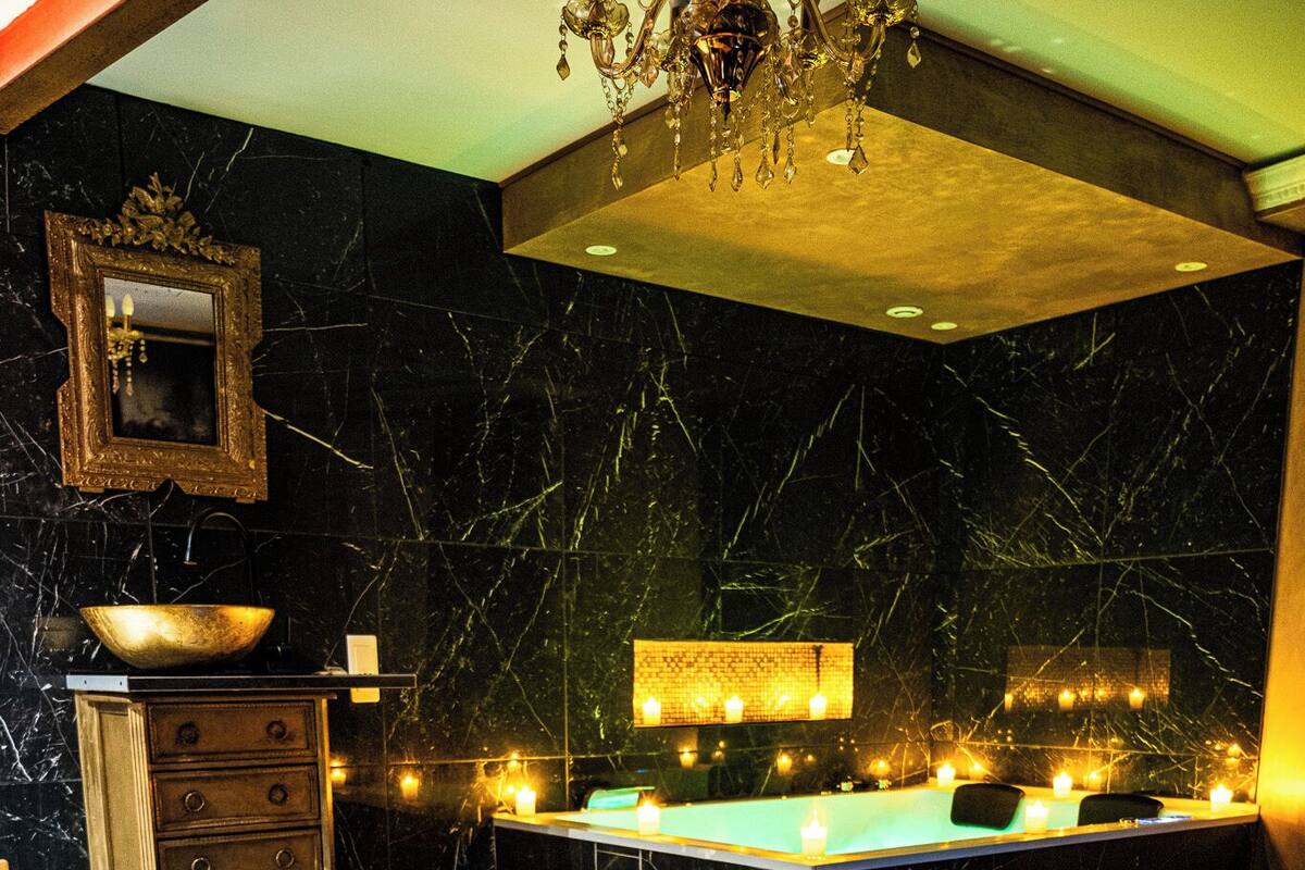 A spa room with a massage table, a bathtub, and a mirror on the wall.