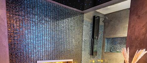Un baño moderno con una bañera grande, un muro con mosaicos y velas.