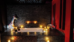 A spa area with a bathtub, candles, and a decorative giraffe statue. - Suite Romantique (Narbonne)