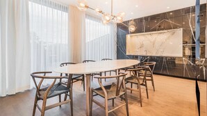 A modern dining area with a round table and wooden chairs, a chandelier, and a large mirror on the wall. - Luxury Residence near Parliament (Vienna)