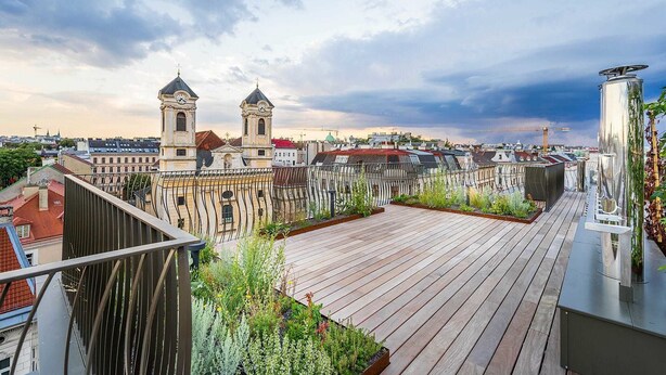 A rooftop terrace with a view of historic buildings, including a clock tower, and a modern sculpture. - Luxury Residence near Parliament (Vienna)