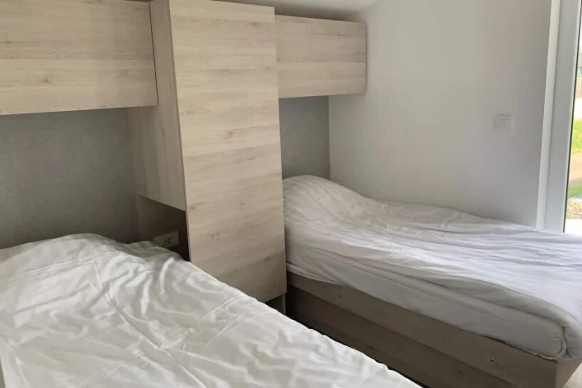 Un dormitorio con dos camas y cabeceros de madera, además de una ventana.