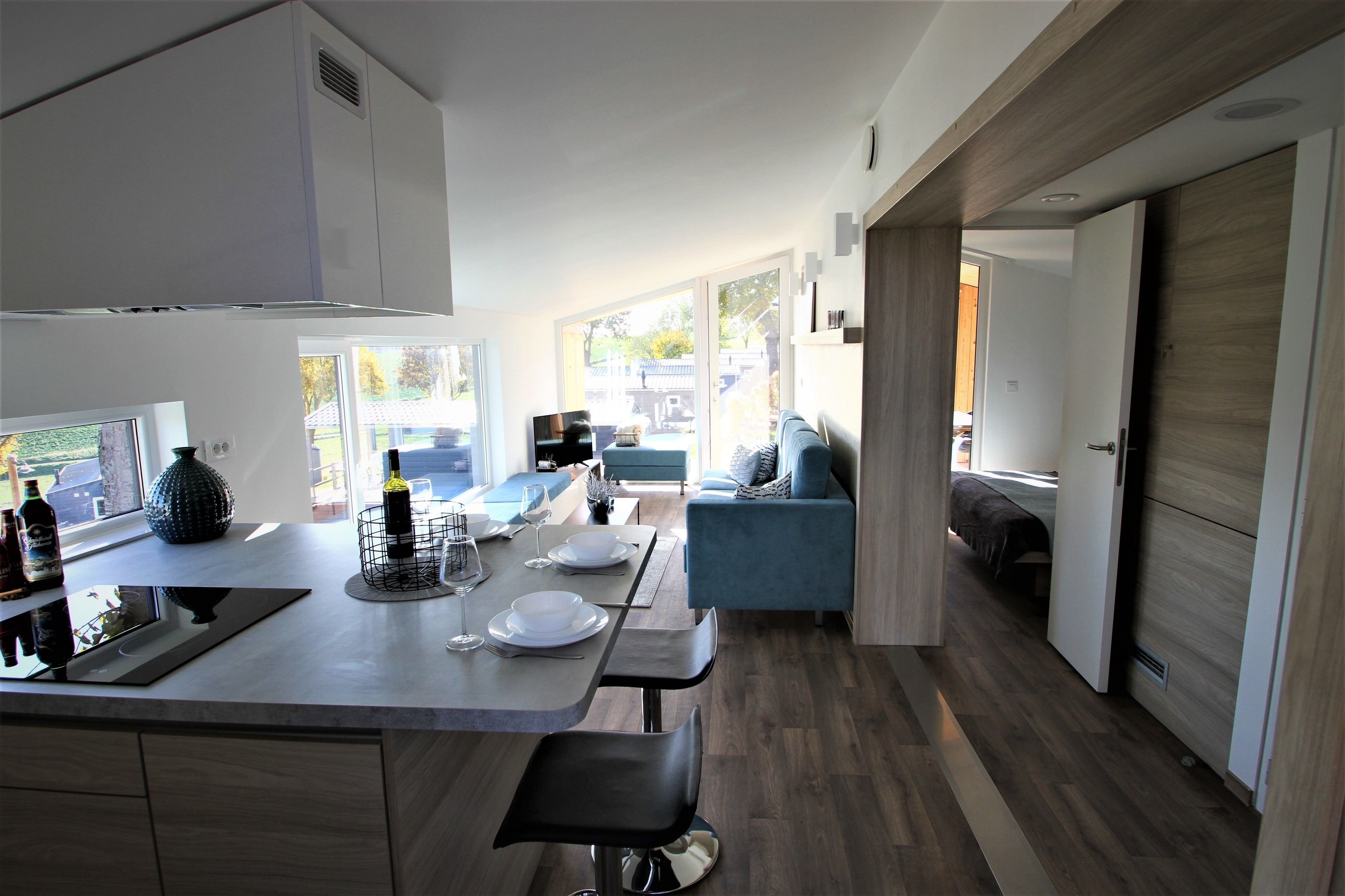 A modern kitchen with a dining area, a sofa, and a view of the outdoors.