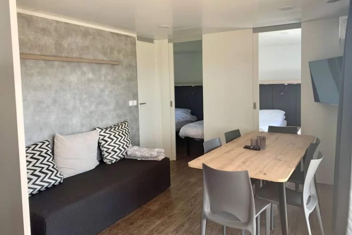 Una habitación compacta con sofá, mesa de comedor y sillas.