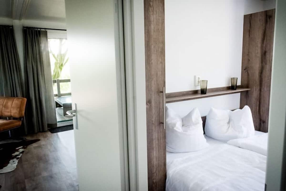 Una habitación de hotel moderna con una cama, una silla y vistas al exterior.