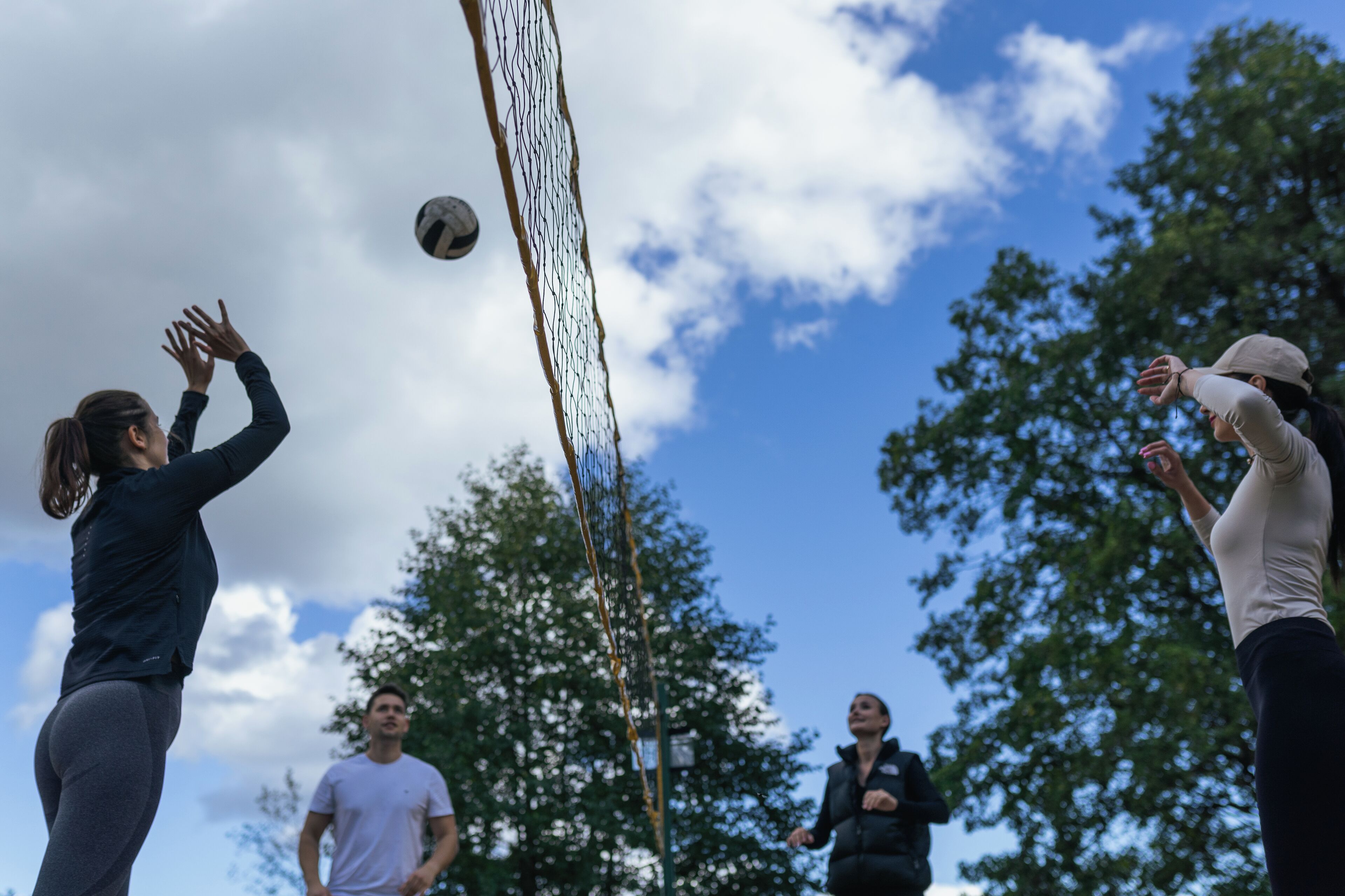 A group of people playing volleyball outdoors.