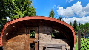 A wooden cabin with a curved roof, a wooden door, and a bench outside. - Villa Nad Kalwa (Pasym)