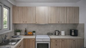 A modern kitchen with wooden cabinets, a stainless steel sink, a stove, and a coffee maker. - Mignon & Teak (Athens)