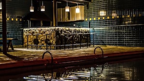 A poolside area with a stone wall, a bar counter, and a tiled wall in the background. - Casa de Campo com Piscina Aquecida (Poços de Caldas)