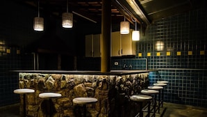 A bar area with a stone wall backdrop, bar stools, hanging lights, and a tiled backsplash. - Casa de Campo com Piscina Aquecida (Poços de Caldas)