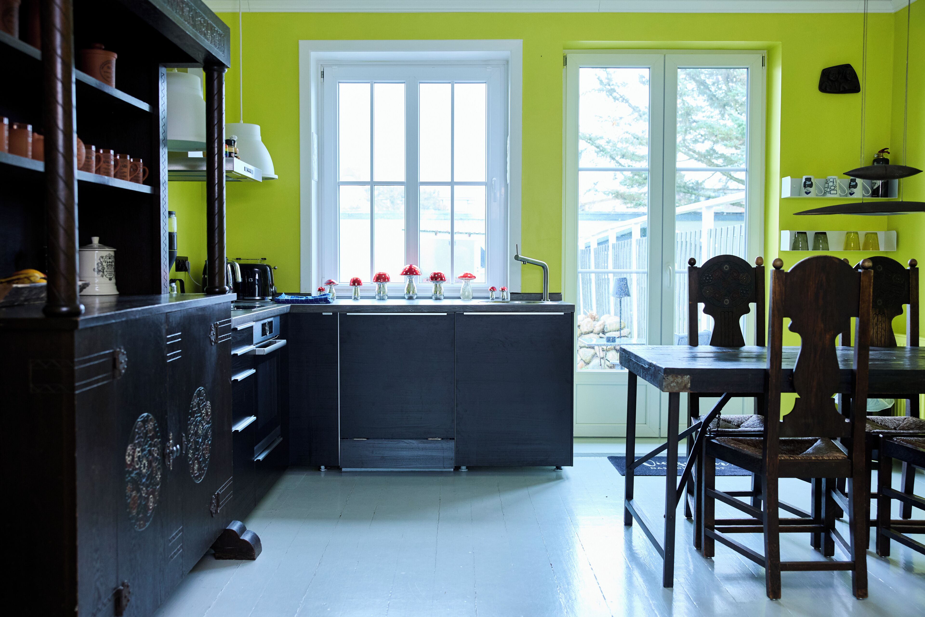 A kitchen with a central island, a dining table with chairs, and a window with a view.
