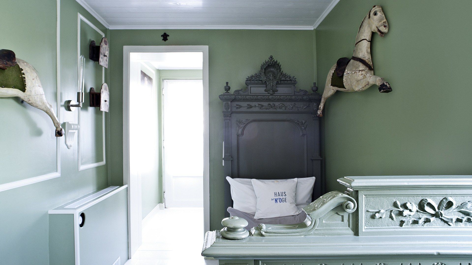 Une chambre comprenant un lit, une commode et une sculpture équestre fixée au mur.
