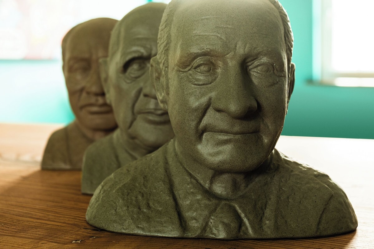 A row of bust sculptures on a wooden surface.