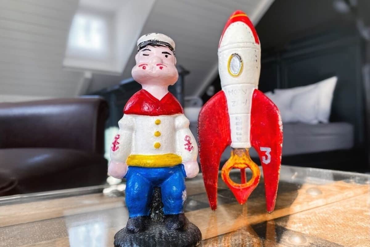 A figurine of a man in a sailor outfit and a red rocket on a glass table.