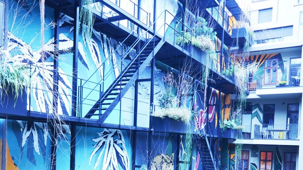 A multi-story building with balconies, staircases, and a mural with plant life. - Premium Residence near Parliament (Vienna)