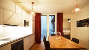 A modern kitchen with a microwave, oven, and wooden dining table with chairs. - Premium Residence near Parliament (Vienna)