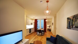 A modern living room with a flat-screen TV, a sofa, and a dining area with a table and chairs. - Premium Residence near Parliament (Vienna)