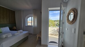 A hotel room with a bed, a small table, a window with curtains, and a balcony door. - Sesimbra Stylish Villa by Homing (Sesimbra)