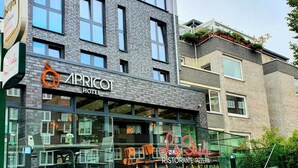 Un edificio moderno con un restaurante llamado "La Strada Ristorante Pizzeria" y un hotel llamado "APRICO Hotel".